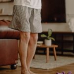 Man practicing balance exercise at home with a focus on legs and barefoot posture.